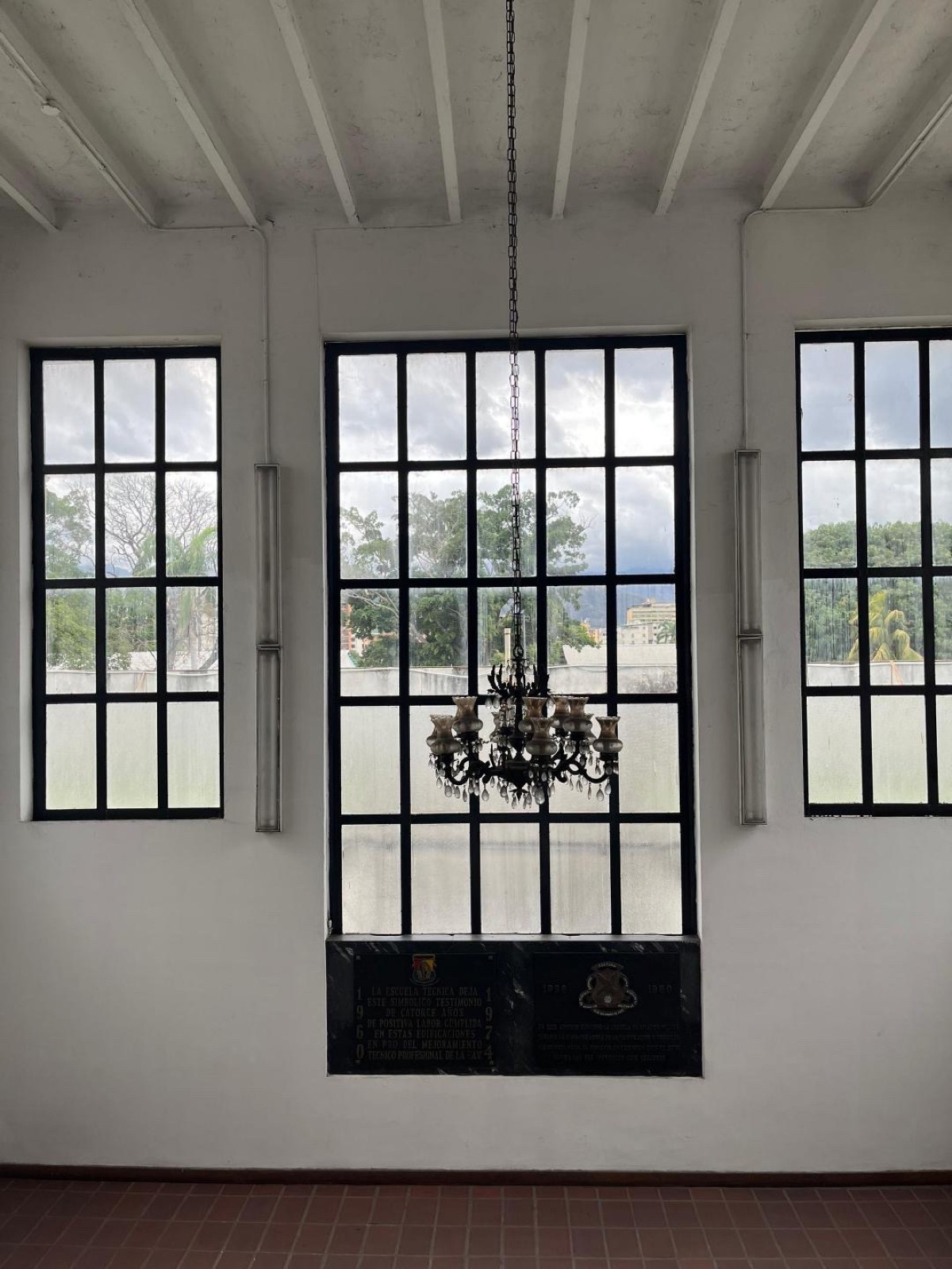Ventanal interior del plantel con candelabro de época y placa conmemorativa de la antigua Escuela Técnica de la Fuerza Aérea Venezolana