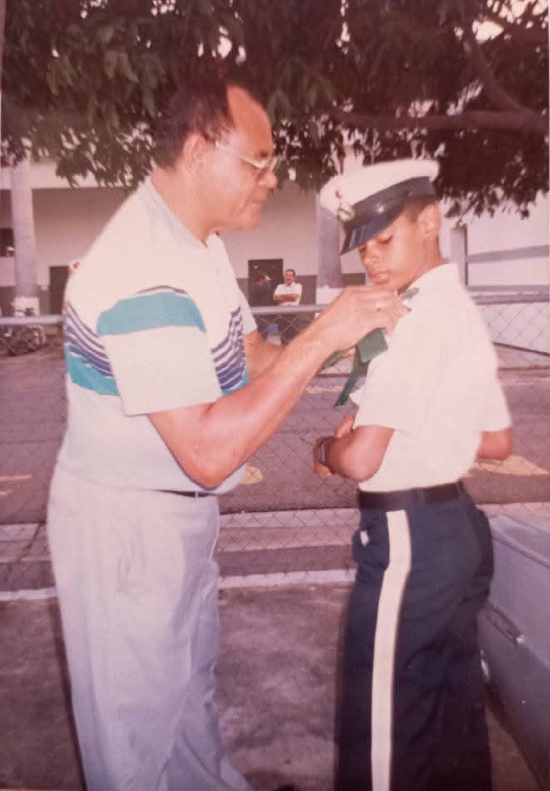 Padre ajustando la corbata del uniforme a su hijo cadete del liceo militar